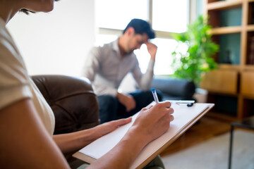 Psychologist taking notes during therapy session.