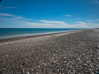 Playa solitaria con conchillas, agua clara y cielo nublado