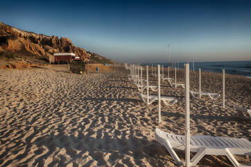 Empty long chairs on deserted beautiful sand beach in Portugal during Covid epidemic and touristic crisis.