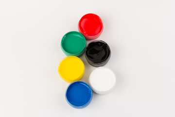 Plastic jars with paint of different colors for children's creativity on white background. Paint bottles for art