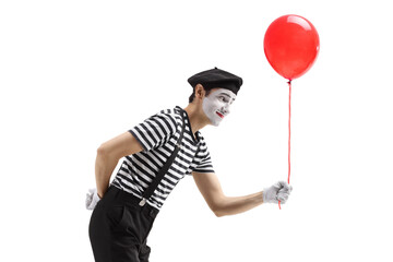 Profile shot of a mime giving a red balloon