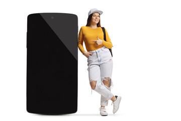Female student leaning on a big smartphone and pointing at it