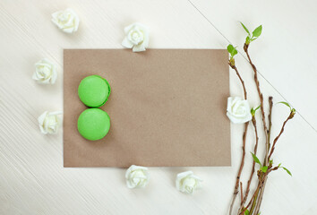 Fototapeta na wymiar 8 March macaroons on envelope mock-up and fresh leaves. Sprig concept, International Womens Day celebrate. Copy space.