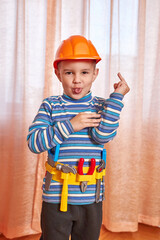 The boy is in a good mood with a toy helmet and tools.