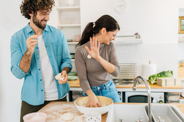 Couple in kitchen having fun and making dough