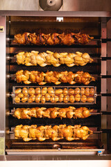 Traditional roasted chicken and potatoes near the entrance to the butcher shop in the city, roasting potatoes and chicken with natural gas