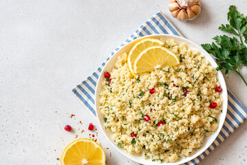 Cooked couscous in a ceramic plate on a white concrete background top view. Maghreb cuisine, vegan food. Copy space for text