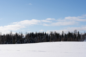 white fluffy snow and on it stands a large hunting tower built of wood