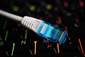 Makro closeup of isolated blue white network connector cable on illuminated computer keyboard