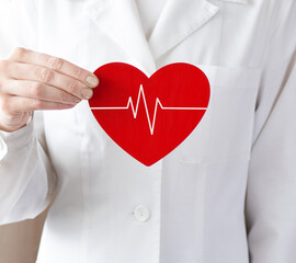 Woman doctor holding a red heart. Medical help, prophylaxis or insurance concept. Cardiology care,...