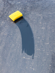 A clean strip on a dirty surface is made with a wet yellow sponge. Cleaning, washing dirty surfaces