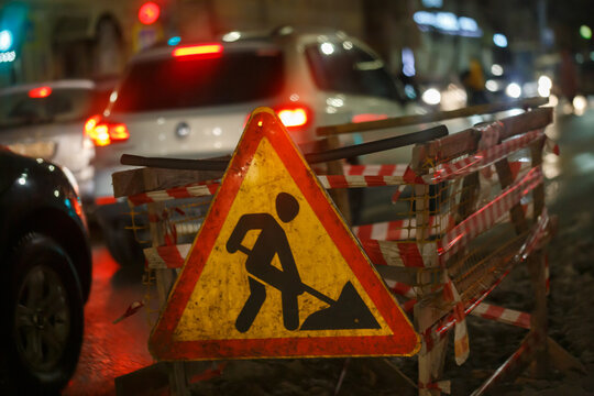 Road works ahead sign at winter night street near pit