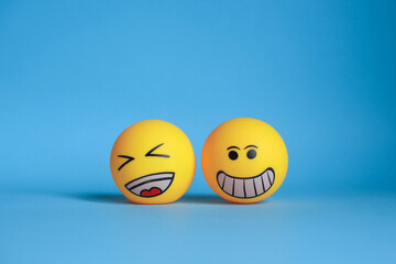 Smiley emoticon with laugh emoticon isolated on blue background