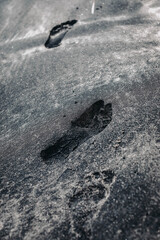 Human footprint imprinted in the volcanic black sand of the balinese beach. Bali, Indonesia
