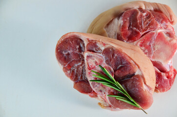 pieces of raw pork steaks, with ingredients for cooking, served on woodenboard. with rosemary, cherry tomatoes, black pepper and olive oil on the table Concept of food preparation on white background