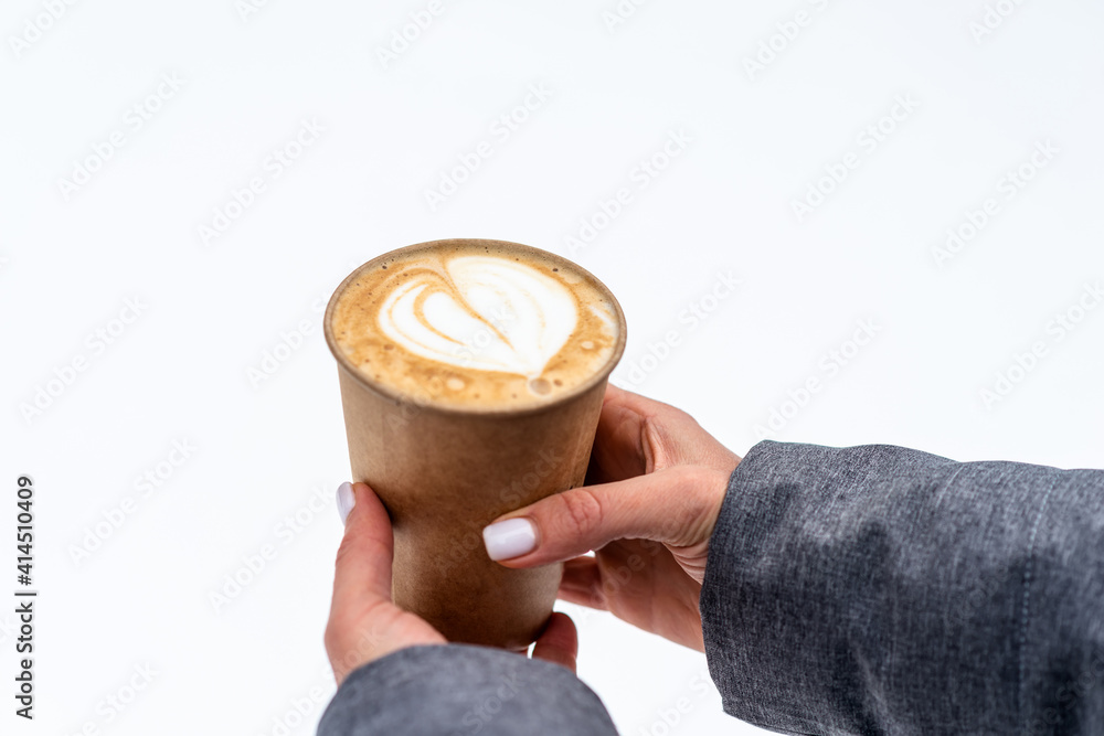 Wall mural Girl holding a glass of cappuccino over the snow close-up.