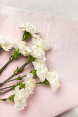 Bouquet of white carnations on pink paper
