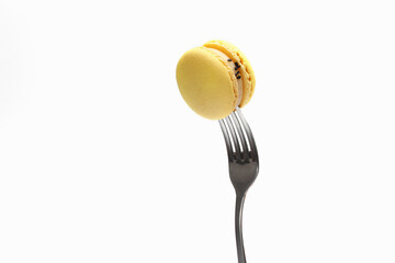yellow macaroons on a fork, top view. Sweet french macaroons cake isolated on white background.