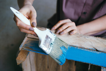 Close-up fwmale hands with brush painting wooden box. Handmade concept. Selective focus,blurred