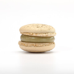 One cake of macaroni pistachio color. Delicious caramel macaroon isolated on black background. French sweet cookie