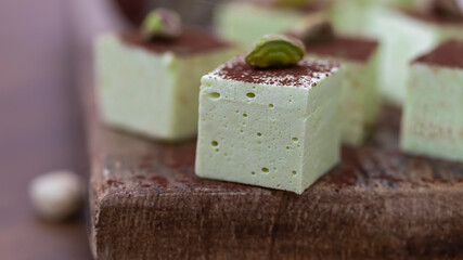 Handmade souffle candy with pistachioon a wooden background. Homemade sweets or candies. Pistachio souffle.