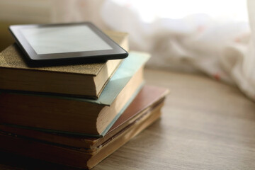 Stack of vintage books and e-book reader on top. Selective focus.