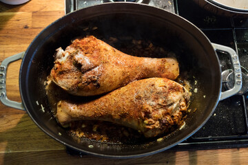 marinated and spiced turkey leg with various vegetables in the casserolle, cooking on the stove.
