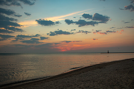 blue and pink cloudy morning sky. sunlight peeking through clouds at dawn. reflection of sun on lake. sunrise at the beach.