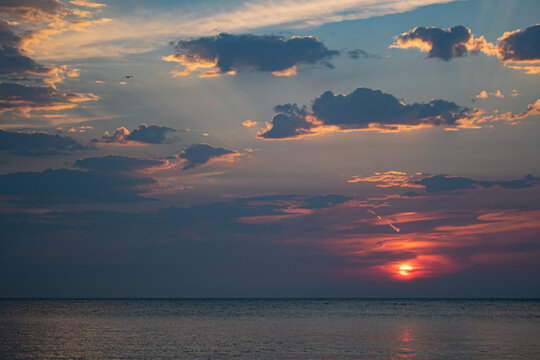 sunrise at dawn over the lake on the beach. bursts of the rising sun and pink in the morning sky.. cloudy morning sky with sun rising.