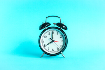Classic alarm clock indicates 8 o'clock isolated blue background