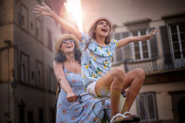 A mother riding a bicycle and her daughter is sitting on the handlebar