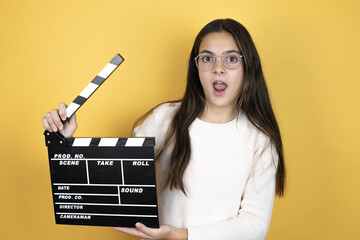 Beautiful child girl wearing casual clothes holding clapperboard very happy having fun