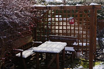 wooden, openwork gazebo covered with snow in the garden 