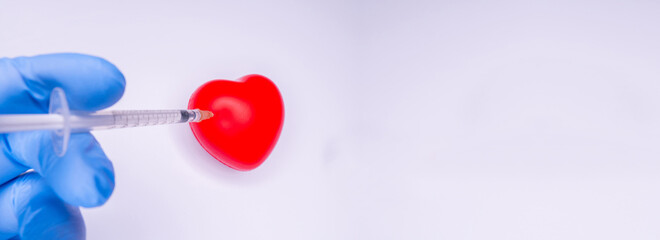 a hand in a medical glove holds an ampoule containing the covid-19 vaccine, invented to prevent the spread of the virus around the world. mask with a red heart on a white background Copy Space