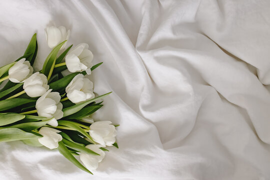 Bouquet of spring white tulips on the bed