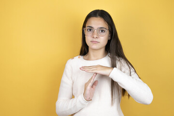 Beautiful child girl wearing casual clothes Doing time out gesture with hands, frustrated and...