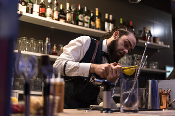 Expert barman is making cocktail at night club.