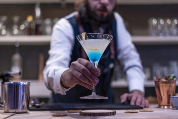 Expert barman is making cocktail at night club.