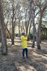 Obraz premium Vertical photo of the a Woman makes photos with analog reflex camera in the forest