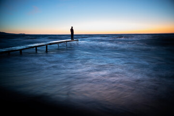 Fototapeta premium person walking on the pier at sunset
