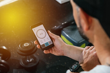 A man with a smart phone in the gym. Looking at the screen of the smart phone. With dumbbells on the floor. health and wellness concept.
