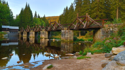 Fototapeta na wymiar The old wooden bridge with small hydroelectric power station in Sumava, Czech republic
