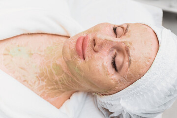 Obraz na płótnie Canvas Dried enzyme mask on the face and neck of a woman. Rejuvenation and facelift in a cosmetology clinic