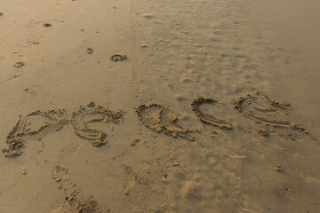 Panoramic landscape view of 'Peace' word written or made in yellow sand on a sandy beach in India
