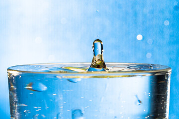 Fototapeta na wymiar water drop splash in a glass. Blue background.