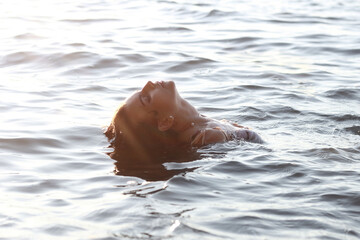 Beautiful curly happy girl in blue clear water.