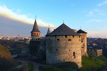 Fototapeta na wymiar Scenic landscape photo of ancient stone fortress in the city of Kamianets-Podilskyi during winter sunset. Panoramic dramatic sunset sky. Famous touristic place and romantic travel destination. Ukraine