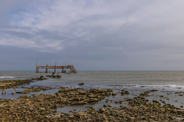 Fototapeta na wymiar Old crumbling pier by the sea