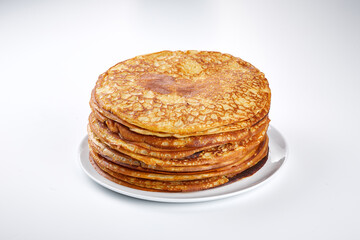 Stack of thin pancakes on a white plate and on a light background. The side view. Maslenitsa.
