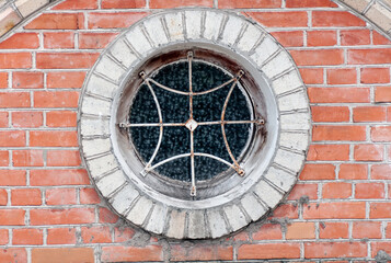 Fototapeta na wymiar round window with grille on the brick wall closeup